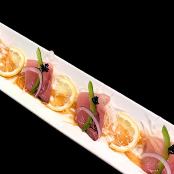Sushi Hiro's tuna sashimi with lemon, red onion, and asparagus on a white platter.
