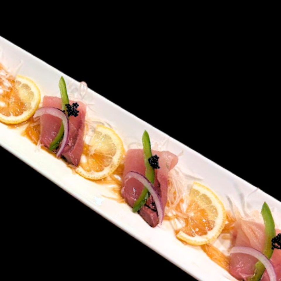 Sushi Hiro's tuna sashimi with lemon, red onion, and asparagus on a white platter.